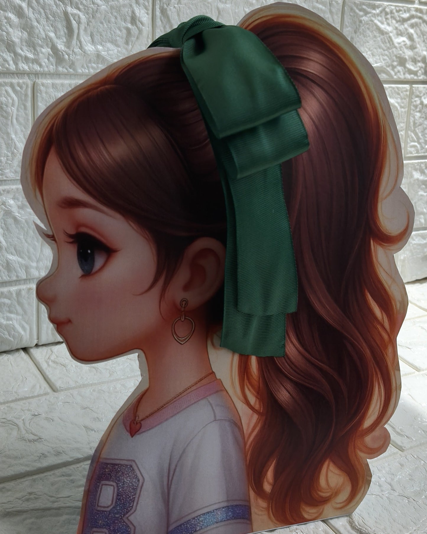 Illustration of a girl with brown hair in pigtails wearing a TinyShiny Bow Dark Green color