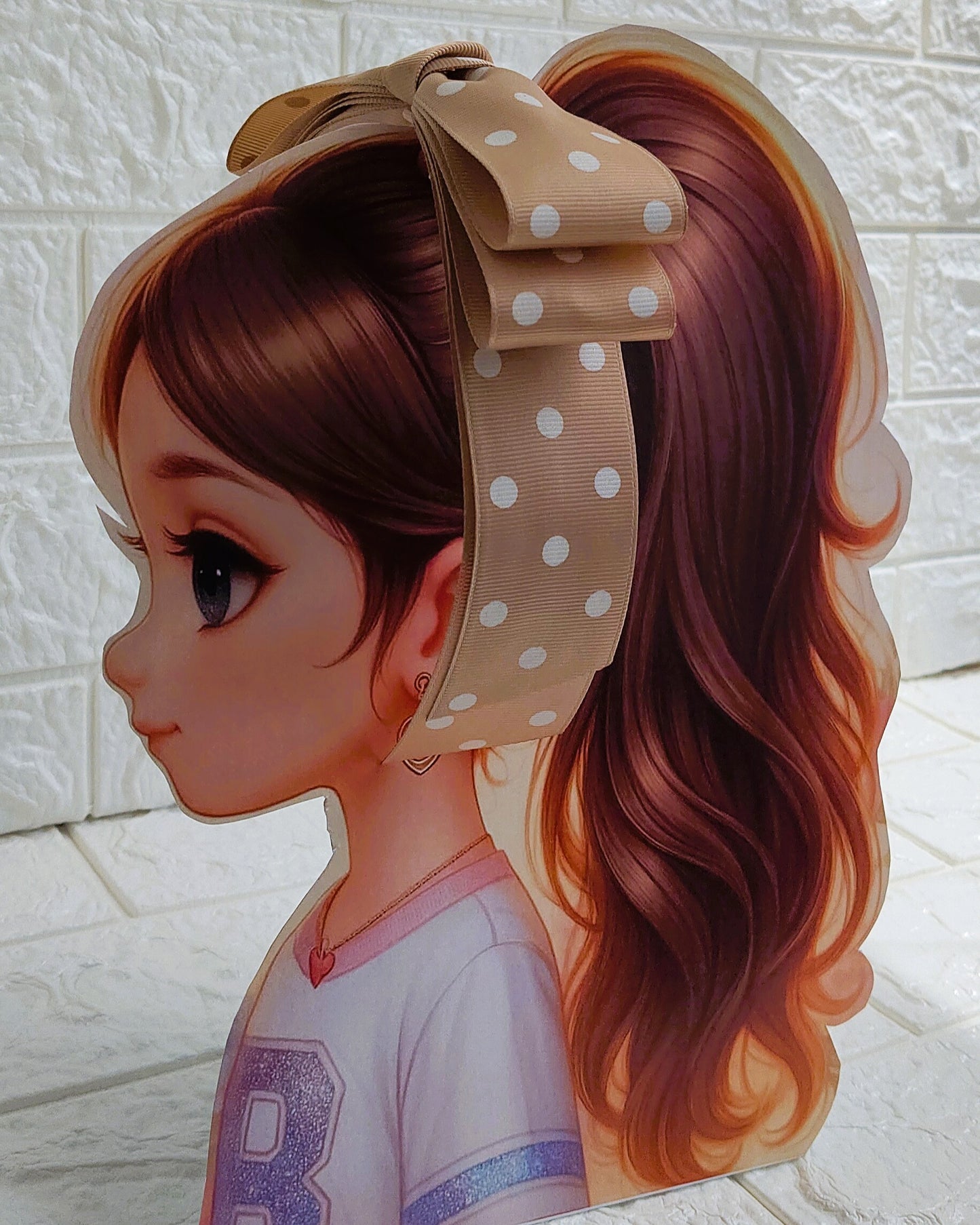 Illustration of a girl with brown hair in pigtails wearing a TinyShiny Bow Desert Brown with white dots color
