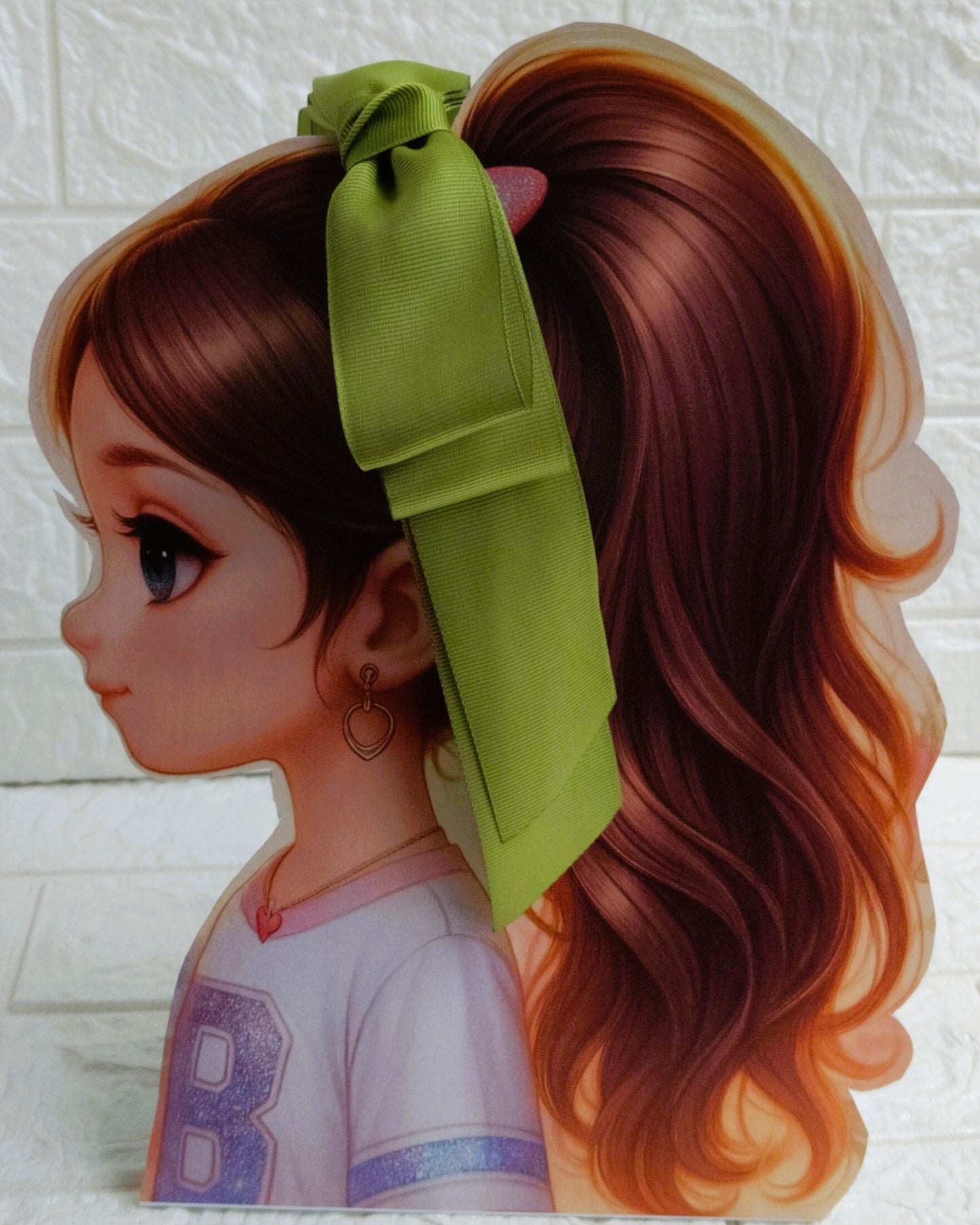 Illustration of a girl with brown hair in pigtails wearing a TinyShiny Bow Leaf Green color 