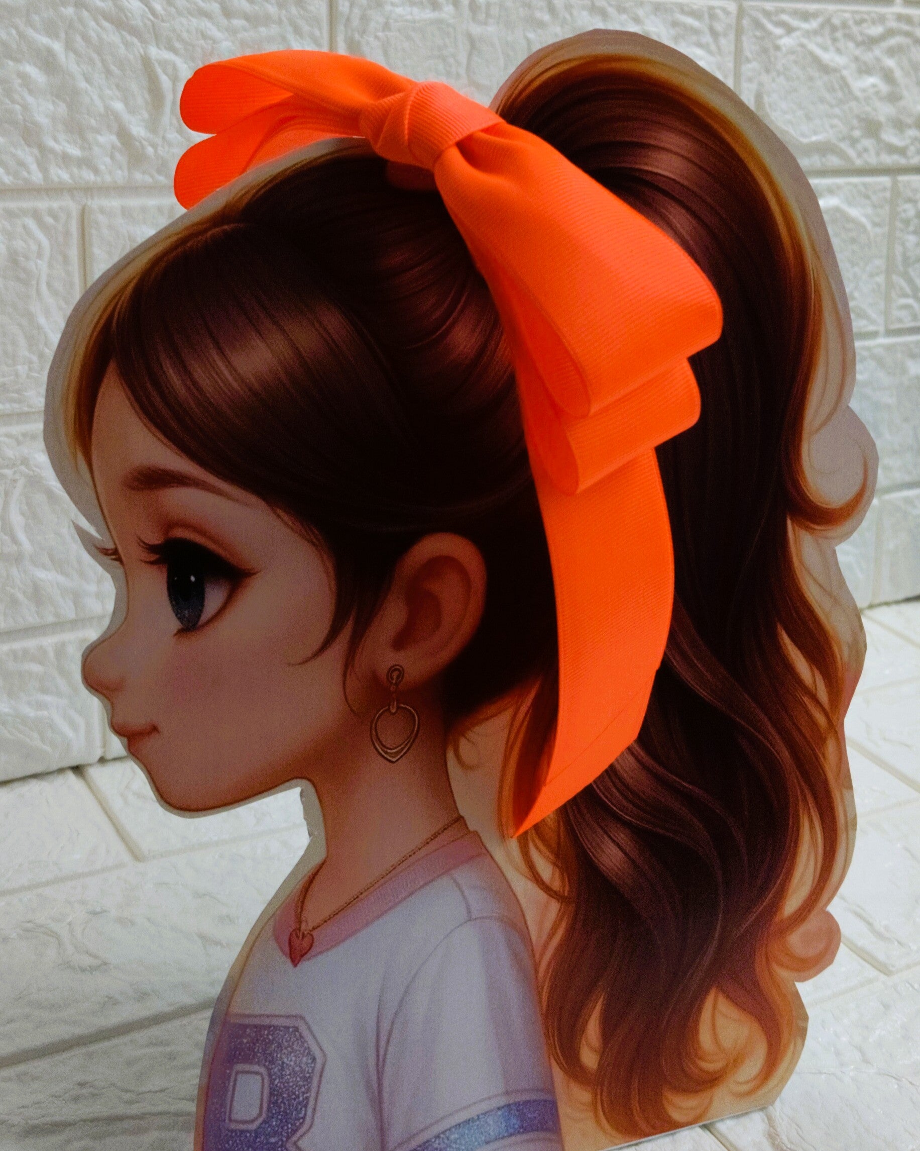 Illustration of a girl with brown hair in pigtails wearing a TinyShiny Bow Neon Orange color 