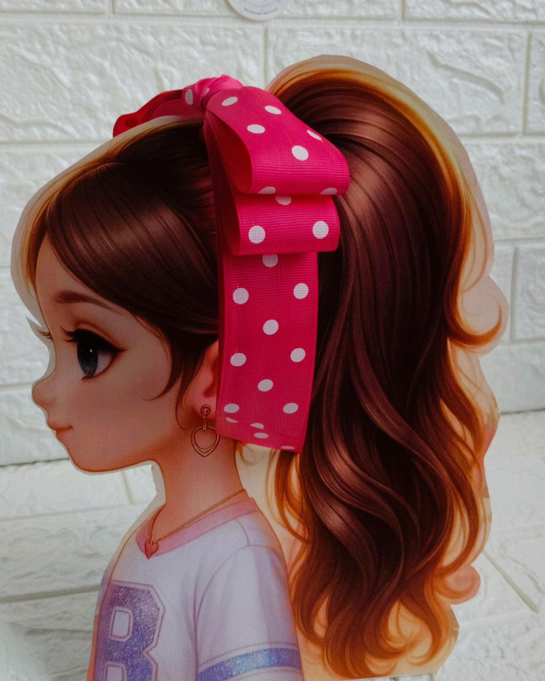 Illustration of a girl with brown hair in pigtails wearing a TinyShiny Bow Pink with white dots color 